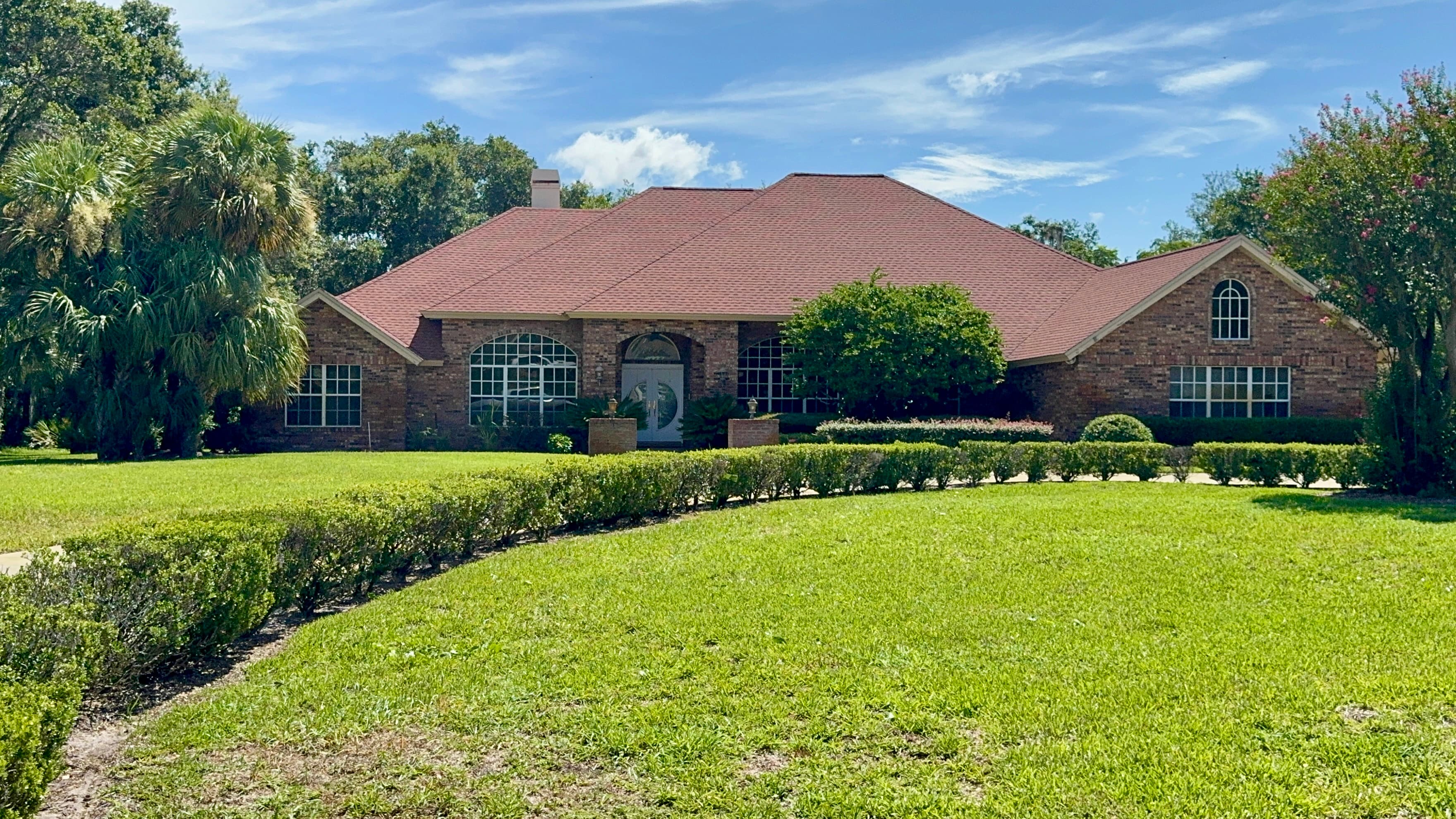 Bloomingdale neighborhood stone and brick estate home in Valrico FL with palm trees representing the Valrico vs Plant City real estate comparison for buyers in 2026